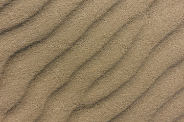 Close up sand texture on the beach with waves as background, top view