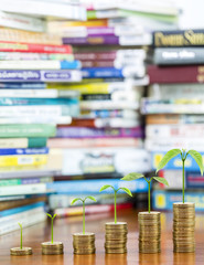 Tree growing on money coins stack arranged as a graph with blurred pile of book as background, concept of educational advancement and saving money