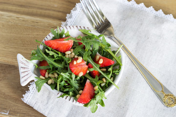 Salad of arugula and strawberries with pine nuts. Top view.