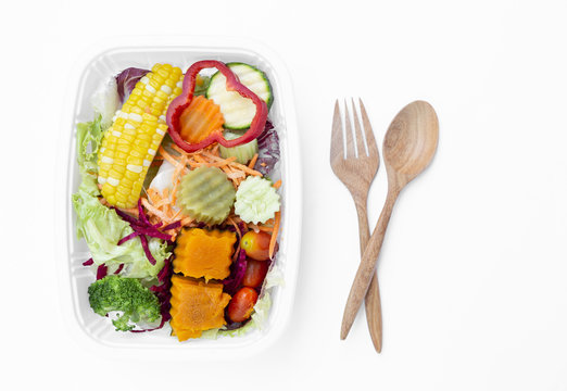 Fresh mixed salad in white plastic container with wooden fork and spoon isolate on white background, diet food, healthy food