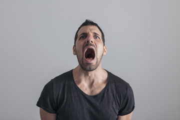 close portrait of a young handsome man on a neutral background with a worried expression, screaming scared