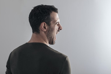 close portrait of a young handsome man on a neutral background with a worried expression, screaming scared