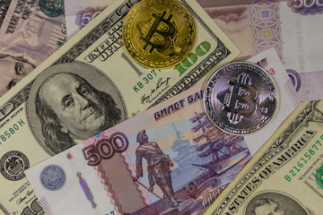 Golden and silver bitcoin on background of us dollars and russian rubles