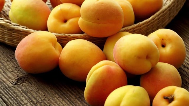 Ripe juicy apricots in a basket on a wooden background