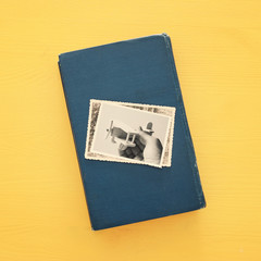 top view of photos over old book on yellow wooden background.