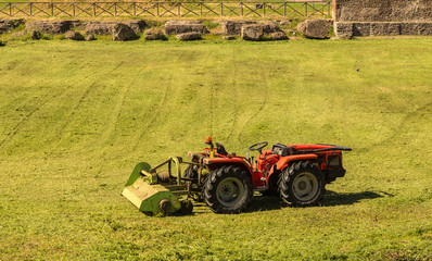 Fototapeta premium Small tractor cutting grass in foro romano ,rome
