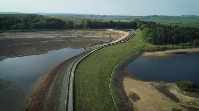 4K aerial drone shot of dried up reservoir on sunny day.