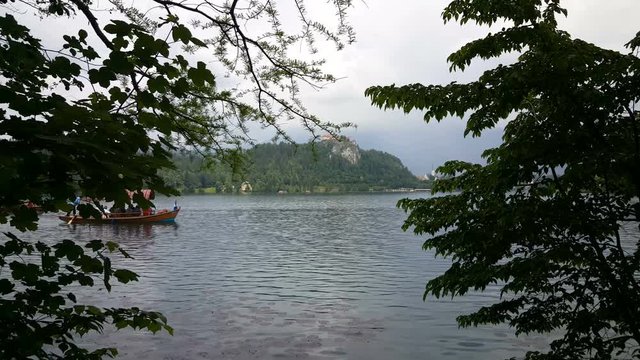 Traditional wooden pletna boat with tourists on lake Bled