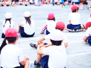 運動会　体育座りをしながら見学している子ども達