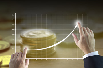 Businessman’s hands drawing a line graph showing of business growth and success with golden tone...