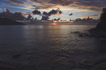 Stunning tropical sunset. Lots of clouds in the sky. In the frame there is a small part of the shore.