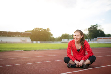 Young woman runner resting after workout session on sunny morning.Female jogger taking a break from running workout.