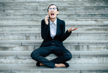 It's a terrible day. Tired and frustrated woman in a business suit and glasses sits on concrete steps with a phone in her hand.