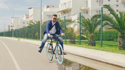 Happy business man fun riding on bicycle on puddle and smiling