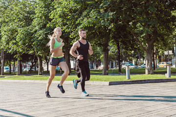 Obraz premium Pretty sporty woman and man jogging at city