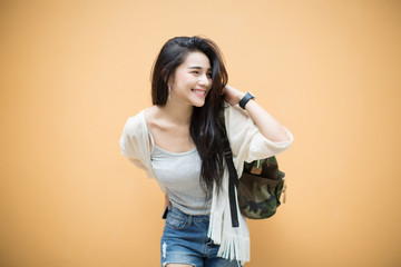 lifestyle fashion portrait of young stylish hipster Asia woman on orange background