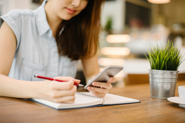 A woman holding and using the smart phone in modern cafe