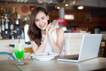 Beautiful Asia woman working on her laptop and smart phone on a stylish urban restaurant