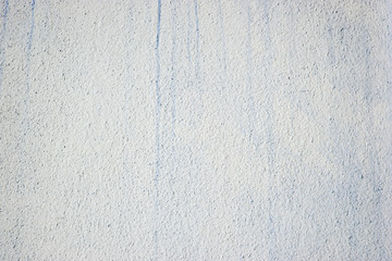 Painted light rough wall with stains of blue paint