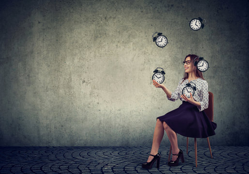 Woman juggling with alarm clocks