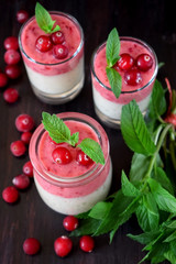 Two layered smoothie with cranberry and banana in a glass jar against the dark background