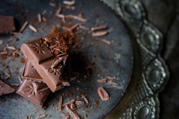 Pieces of chocolate and cacao’s dust on a vintage plate.