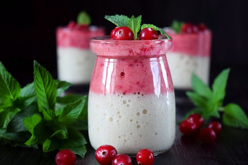 Two layered smoothie with cranberry and banana in a glass jar against the dark background