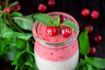 Two layered smoothie with cranberry and banana in a glass jar against the dark background