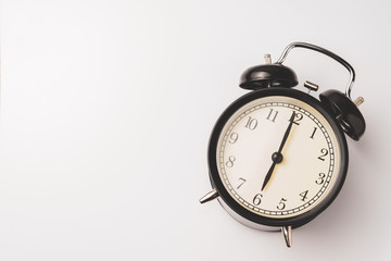 Black vintage alarm clock show 6 o'clock on white background with copy space
