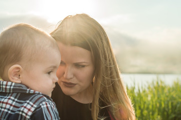 close-up portrait of woman and mother on a background of lake and grass in the sun. concept mother and son