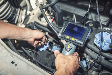 car mechanic check the vehicle engine with borescope camera - obrazy, fototapety, plakaty
