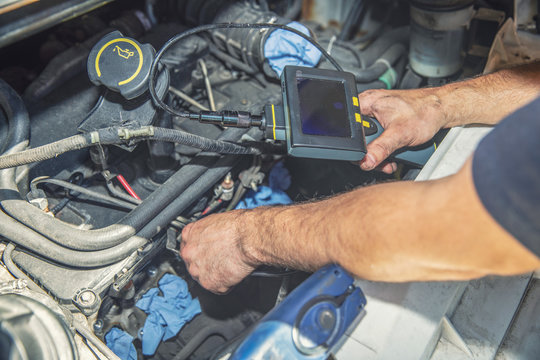 mechanic inspecting car engine with video borescope camera