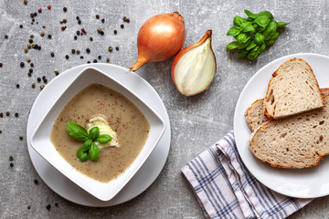 Gray concrete kitchen counter topped with onion soup, bread and pepper seeds