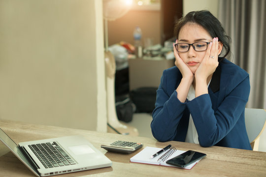 asian businesswoman sitting in office, looking tired.