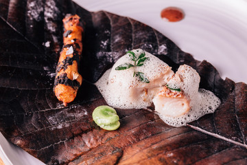 Creative Fine Dining: Fish topping with culinary foam serves with pea and grilled root with salt on torched leaf.