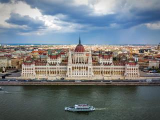 Obraz premium Budapest, Hungary - The Houses of Parliament building and aerial skyline of Budapest at daytime with sightseeing boat on River Danube