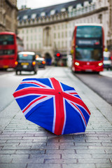 London, England - British umbrella at busy Regent Street with iconic red double-decker buses and...