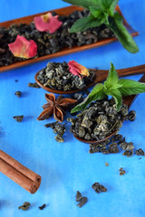 Tea, dried rose petals, spices and mint against the blue background