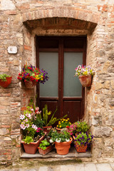 Fototapeta na wymiar Wooden door surrounded by colorful flowers in Tuscany, Italy.