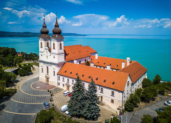 Tihany, Hungary - Aerial view of the famous Benedictine Monastery of Tihany (Tihany Abbey) with beautiful coloruful Lake Balaton and blue sky at background - obrazy, fototapety, plakaty