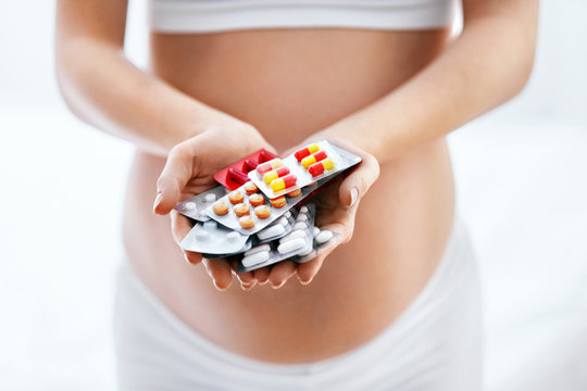 Pregnancy Vitamins And Medications. Pregnant Woman With Pills