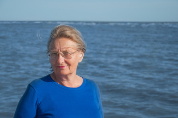 Elderly smiling woman in blue background of the sea