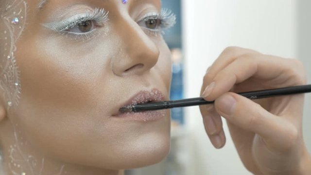 The make-up artist paints the model's lips, with a special brush. close-up