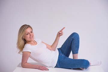 portrait of a beautiful blonde girl on a white background lying on a table.