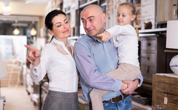Family couple with child girl in furniture showroom