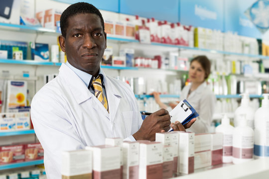 Man pharmacist making notes on clipboard during inventory