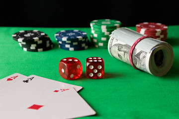 Poker chips, dice, playing cards and twisted 100 banknotes on the green table. Winning concept