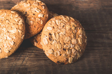 Oatmeal cookies with a sprinkling of oat flakes and seeds on a wooden background
