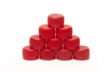 pyramid of red plastic bottle caps on white background