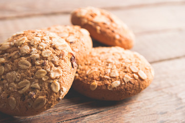 Oatmeal cookies with a sprinkling of oat flakes and seeds on a wooden background